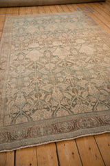 The decorative, time-softened pattern of a vintage Bijar carpet viewed from an angled perspective.