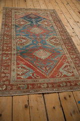 Angled perspective of a vintage Hamadan rug highlighting its red and blue geometric design.
