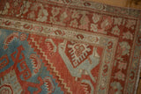 Distressed corner of a vintage Hamadan rug showing worn pile and geometric patterns in blue and red.