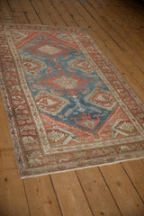 A distressed Persian Hamadan rug with large blue medallions viewed from a low angle.