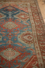Angled view showing the distressed texture and geometric patterns of a vintage Hamadan rug.