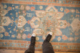 Worn, low pile texture on a distressed Persian runner with a starburst medallion in sky blue and terracotta.