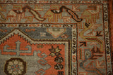 Distressed Malayer rug corner: dusty terracotta ram's horn, serpent border, even wear.
