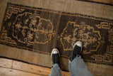 Scale view of an antique Tibetan rug with a coffee brown ground and stylized saffron yellow medallions.