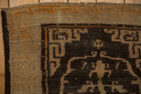Corner of an antique Tibetan rug showing the geometric border, low-pile texture, and finished end.