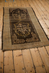 Angled view of an antique Tibetan rug's full length and geometric double medallion.