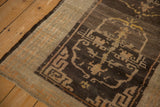 Close view of the antique Tibetan rug's cloudband spandrel in brown and silver with its intact side cord.