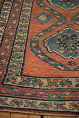 Close view of the hand-knotted texture on the brick red field and dusty teal medallion of an antique Persian rug.