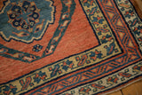 Corner of an antique Persian runner showing its hand-knotted pile in brick red, dusty teal, and saffron yellow.