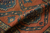 Close view of the antique rug's knot heads and pile in brick red and dusty teal.
