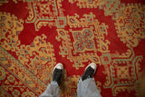 Detailed view of a vintage Oushak carpet's cherry red field with yellow and blue geometric medallions.