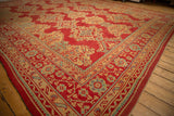 Angled view of a vintage Oushak rug corner showing its detailed geometric border in red, yellow, and blue.