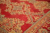 Close-up of saffron and blue diamond medallions on the red, hand-knotted pile of a vintage Oushak.