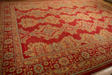 Angled corner view of a vintage Oushak carpet's geometric medallions on a cherry red field.