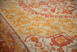 Intricate saffron and tangerine flame-like blossoms on an antique Oushak carpet.