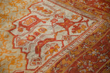 Antique Oushak carpet detail: flame-like tangerine and gold motifs on pale seafoam green ground.