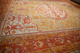 Madder red and saffron gold borders of antique Oushak carpet with nuanced floral designs.