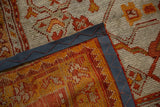 Corner detail of an antique Oushak carpet, showing hand-knotted pile, woven foundation, and sewn binding.