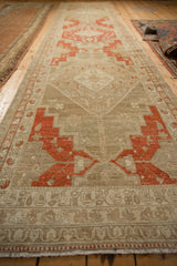 Angled perspective down the length of a distressed Malayer runner with rust geometric medallions.