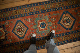 Personal perspective of an antique Heriz runner's geometric medallions in madder red and sapphire blue.