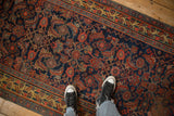 Looking down at the antique Bijar runner's dense Herati motif in cobalt blue, red, and saffron.