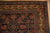 Corner detail of an antique Bijar rug showing its geometric floral border in saffron, blue, and brick red.