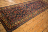 Angled view of an antique Bijar runner with its intricate Herati field and colorful geometric border.