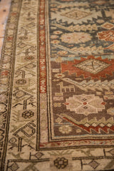 Distressed vintage Malayer runner's beige meandering vine border and dark field with animal motifs.