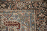 Corner of distressed vintage Heriz rug showcasing its Turtle Samovar border and floral field.