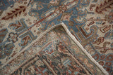 Distressed Heriz carpet corner, revealing worn pile in ivory and denim blue with faint foundation.