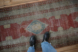 Time-softened texture of a distressed Serbend runner with a blue diamond medallion on a red field.