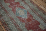 Worn pile detailing the central sky blue diamond medallion on a raspberry red antique Serbend runner.