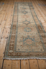 Distressed Karaja rug runner close-up with brown palmette double vine border and dusty blue accents.