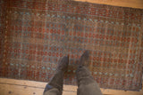 Distressed Belouch rug underfoot, highlighting repeating floral patterns in dusty blue and chestnut tones.