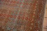 Distressed Belouch rug with chestnut, dusty blue geometric floral pattern and wave border.