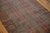 Distressed Belouch rug, featuring geometric germinating blossoms in dusty blue and chestnut.