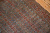 Distressed Belouch rug pattern detail: repeating geometric blossoms, dusty blue and pomegranate red tones.