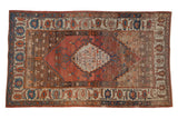 Antique Bakshaish carpet with a stepped medallion on an abrashed ground of terracotta, blue, and coffee brown.