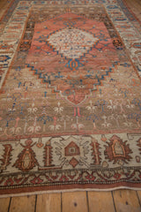 A view down the length of an antique Bakshaish carpet, highlighting the abrashed terracotta and brown field.
