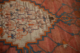 Abrashed terra cotta field meeting a stepped medallion on a low-pile antique Bakshaish rug.