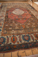 Angled perspective of an antique Bakshaish carpet, highlighting the terra cotta stepped medallion and wide border.
