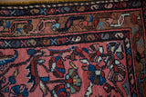 Intricate corner of a vintage Persian rug showing its meandering main border and dusty rose field.