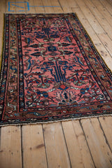 Vintage Persian Mehriban rug from an angle, showing the dusty rose floral field and dark geometric border.