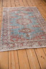 Angled view of the distressed Veece rug showing its low pile and muted red and blue design.