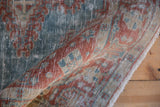 A rolled vintage Veece rug showing distressed, hand-knotted texture in powder blue and red.
