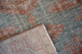 A folded corner reveals the hand-knotted back and distressed, low-pile front of the vintage Veece rug.