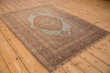 Angled view of an antique Tabriz rug with its large scalloped medallion and floral borders.