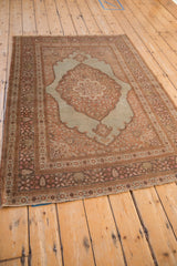 Angled view of an antique Tabriz rug showing the traditional layout with a scalloped medallion and spandrels.