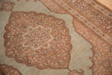 View of the antique Tabriz rug's scalloped medallion, dusty blue field, and ornate floral border.