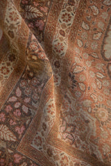 Textural detail of an antique Tabriz rug's low pile, highlighting muted pink and charcoal blossoms.